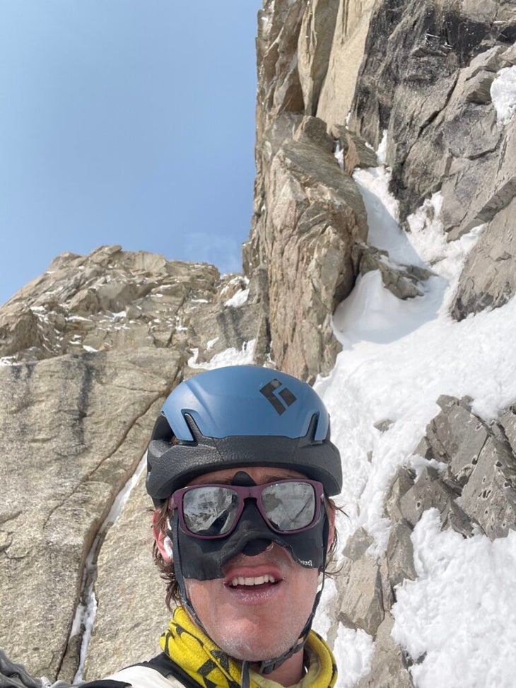 Climber smiles below granite wall in Alaska.